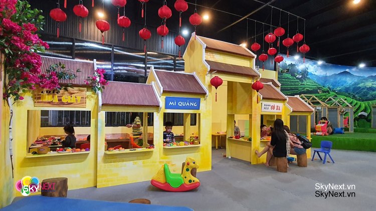 Tất tần tật về RẠP CHIẾU PHIM QUỐC GIA 9 Khu trò chơi mô phỏng chợ làng với gian hàng màu vàng và đèn lồng đỏ treo