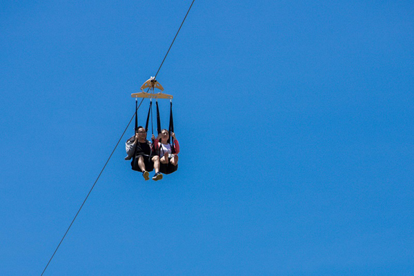 Hai người treo mình trên dây zipline giữa bầu trời xanh