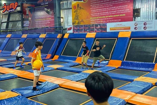 Nhóm người chơi bóng né trên bạt nhún trong sân có lưới cách ly và vùng trung tâm